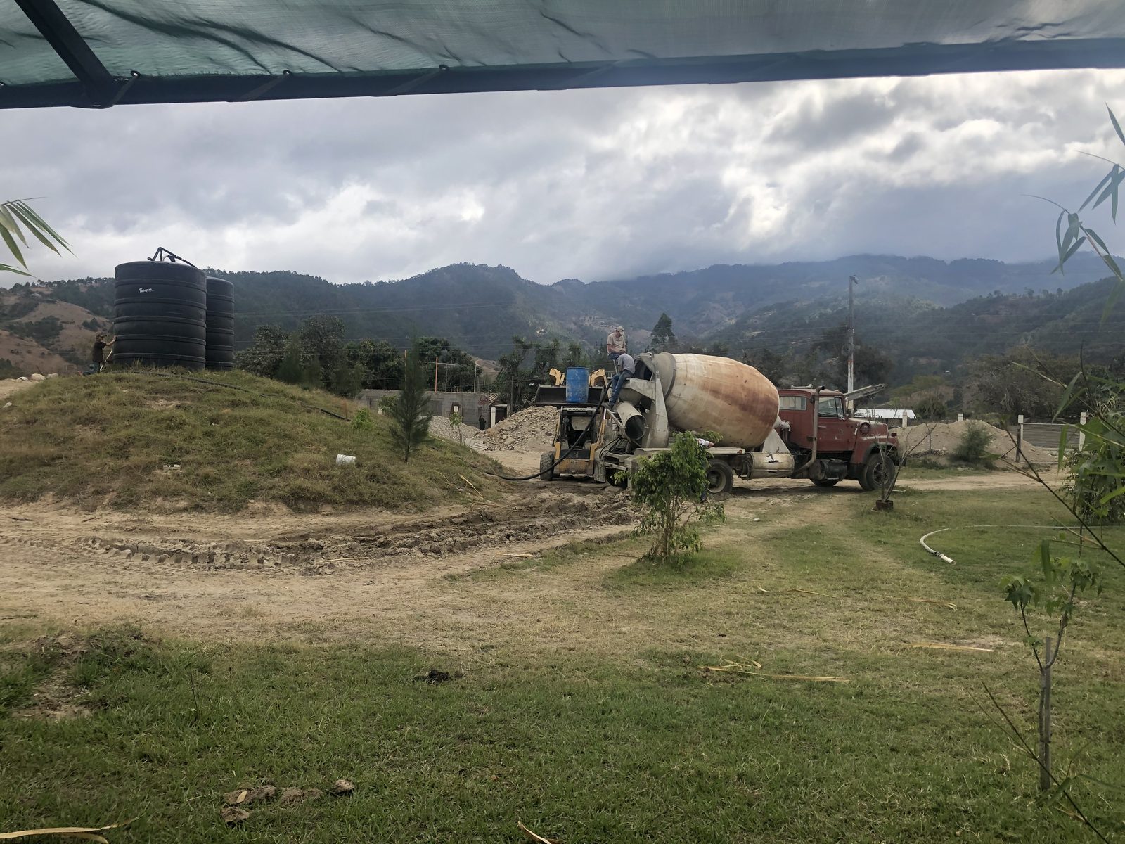 The Adonai hospital construction site with concrete mixer and water tanks against the Guatemalan mountains
